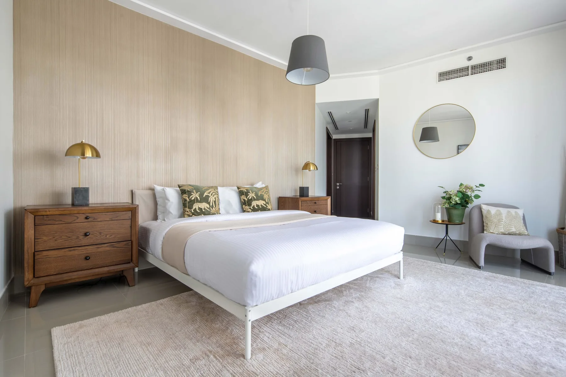 Un dormitorio con una cama bien tendida, mesitas de noche y una silla.