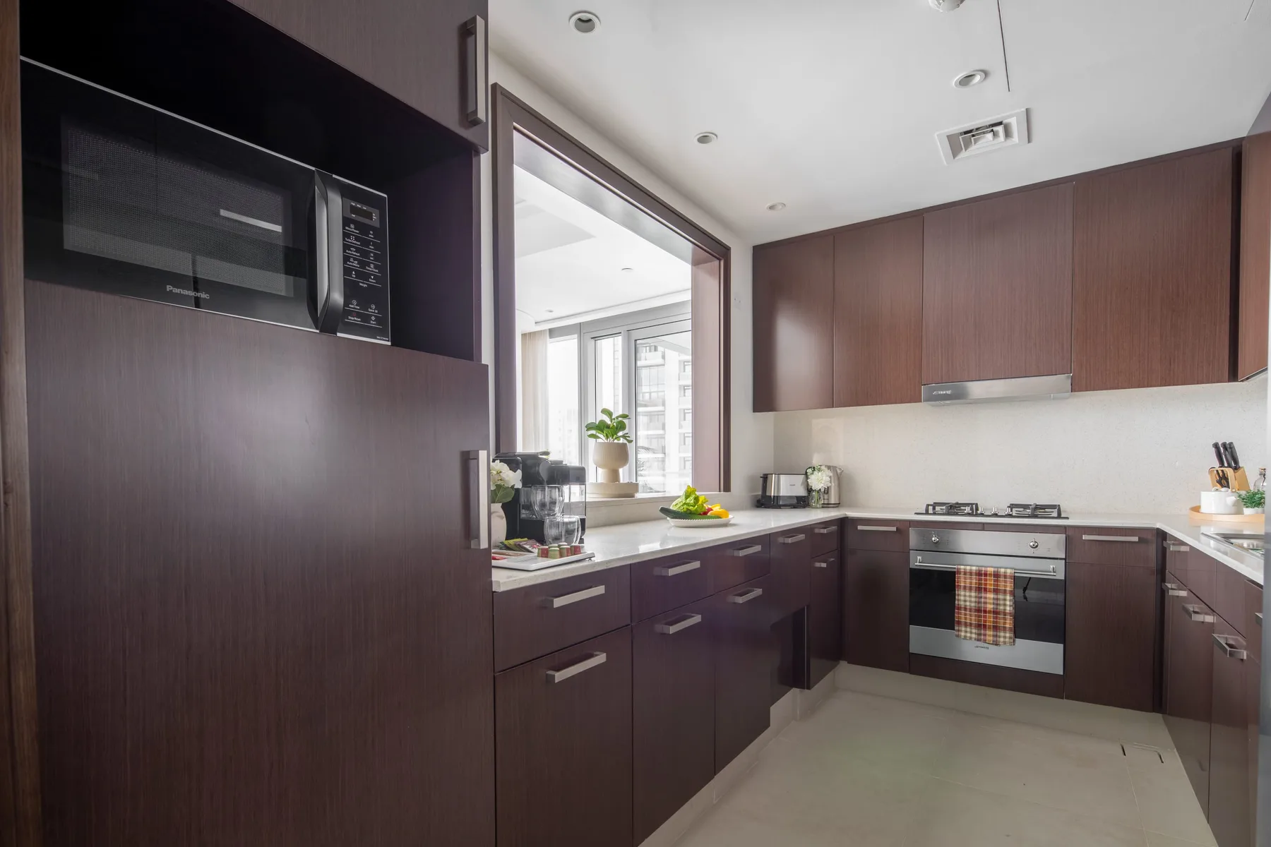 Una cocina moderna con gabinetes oscuros, microondas empotrado y una encimera central.