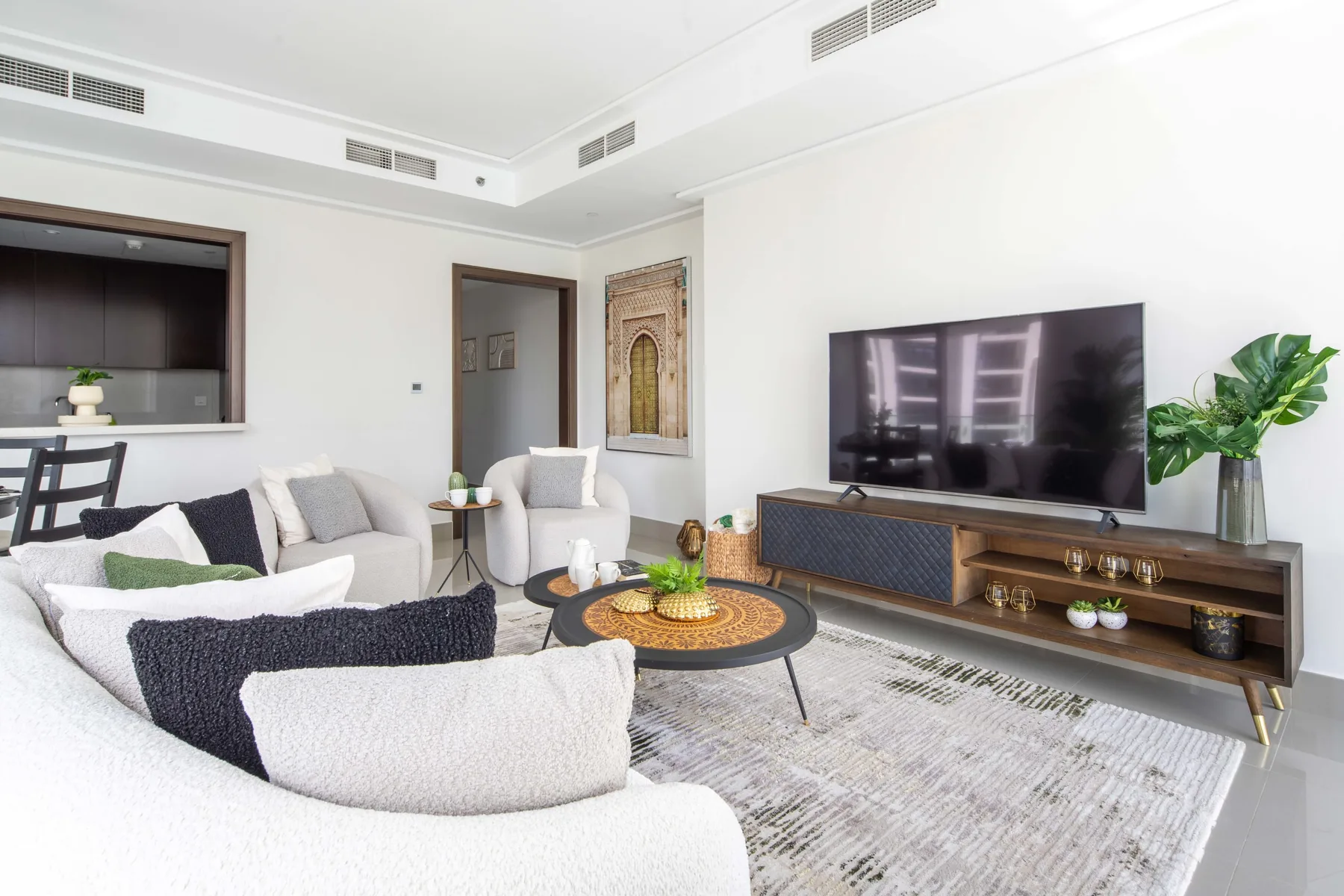 Una sala luminosa con zona de estar, televisor y un mueble bajo para medios.