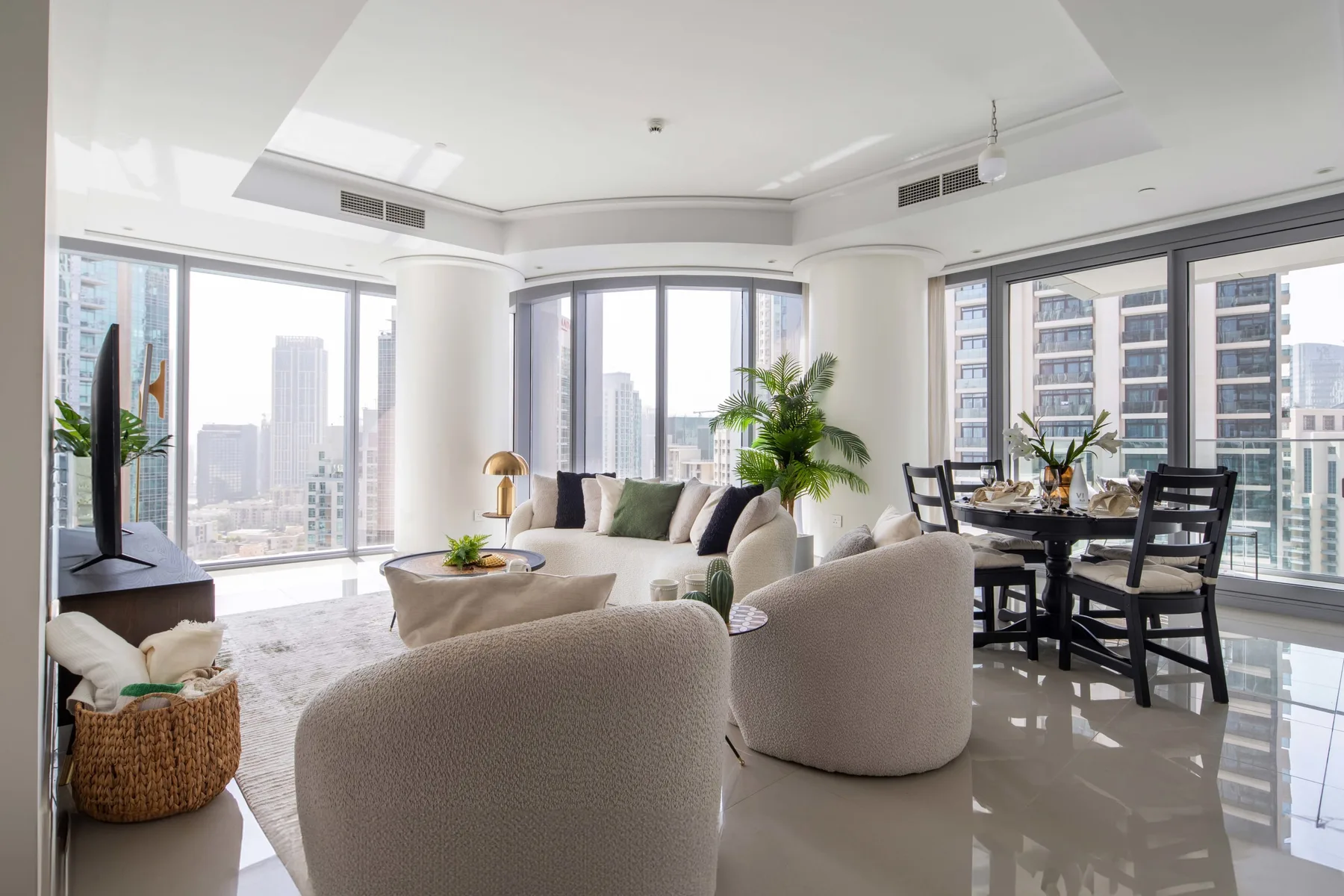Una luminosa sala de estar y comedor con grandes ventanales que dan a edificios de la ciudad.