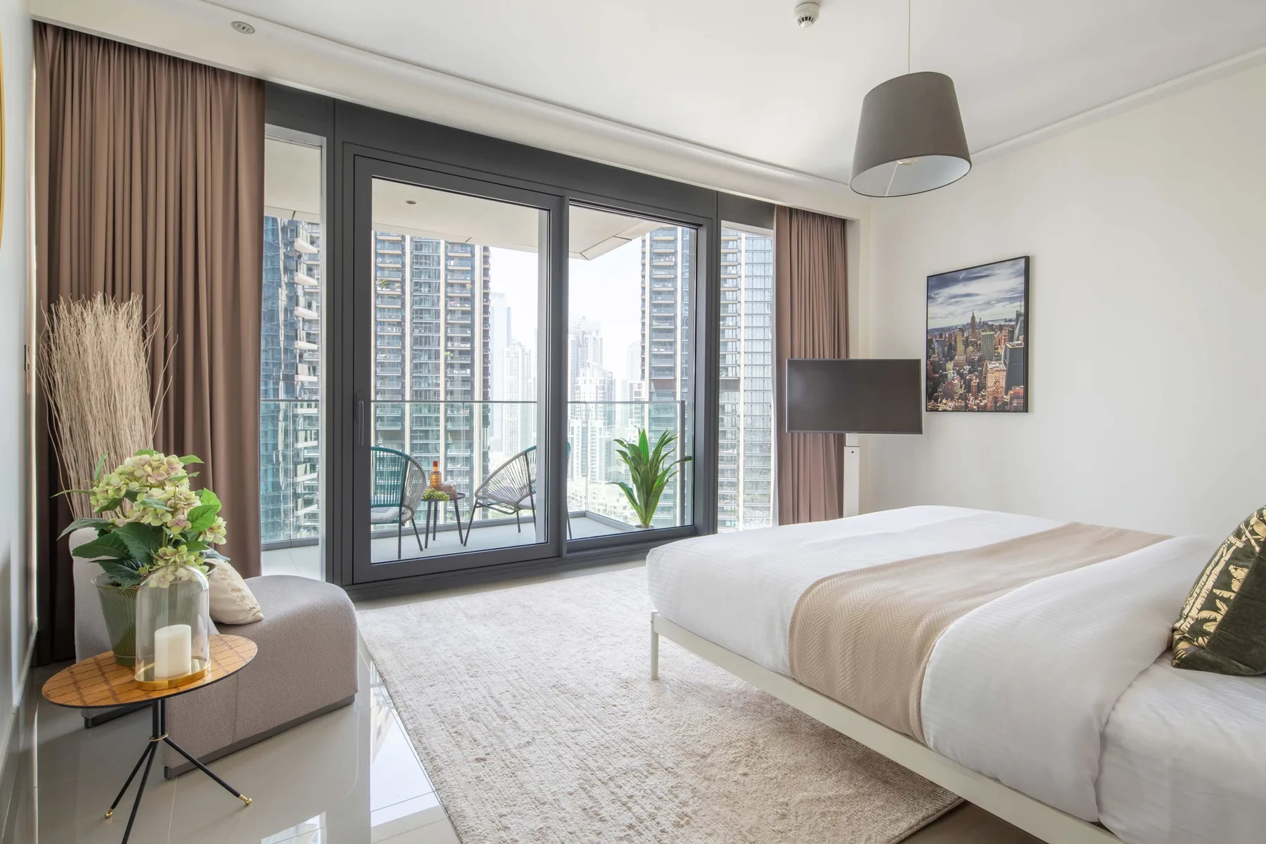 Un dormitorio con una cama grande junto a ventanales que dan a edificios de la ciudad.