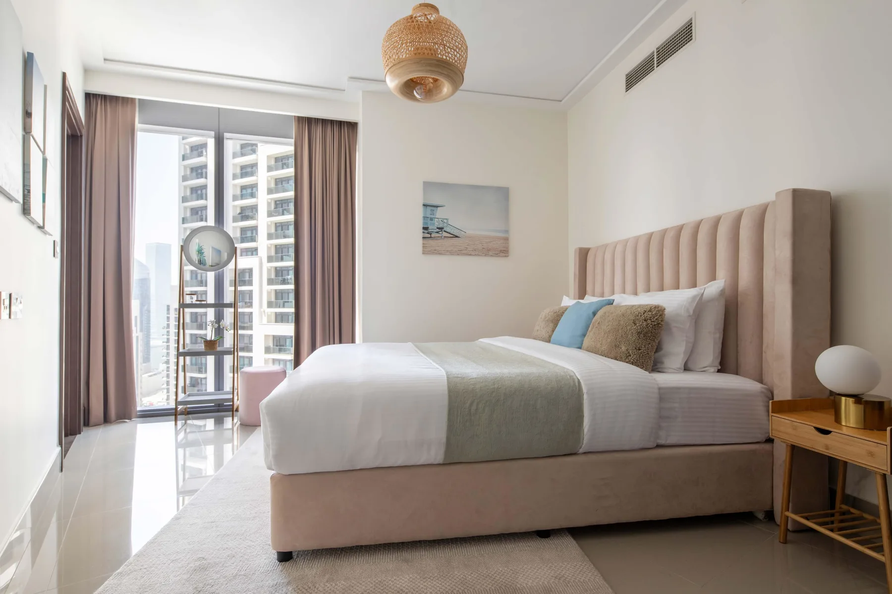 Un dormitorio luminoso con una cama bien arreglada junto a una ventana grande.