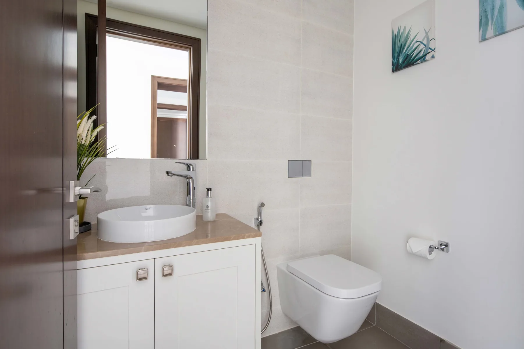 Un baño luminoso con lavabo blanco, espejo e inodoro.