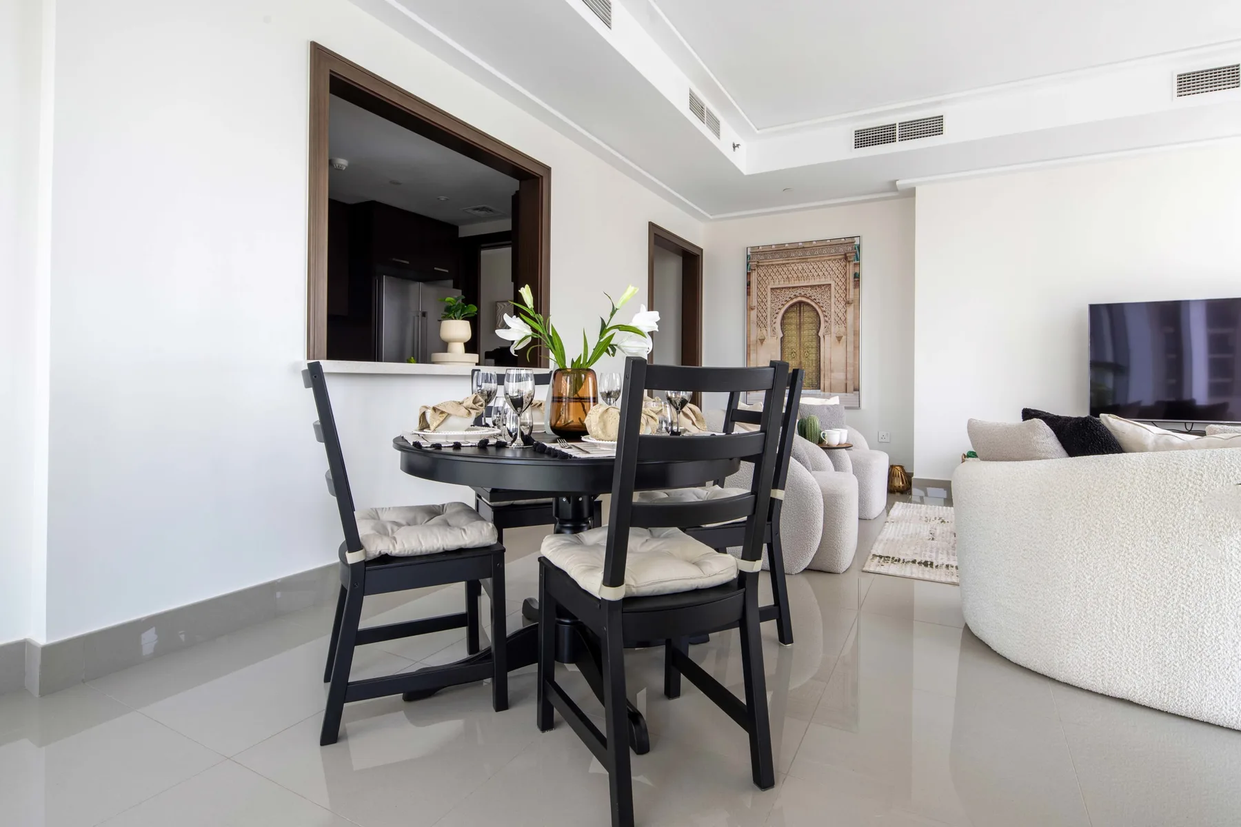 Una luminosa zona de comedor y sala de estar con una mesa junto a asientos blancos.