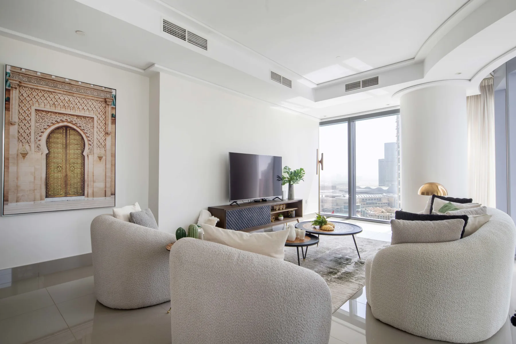Una sala luminosa con asientos curvos, un televisor y grandes ventanales.