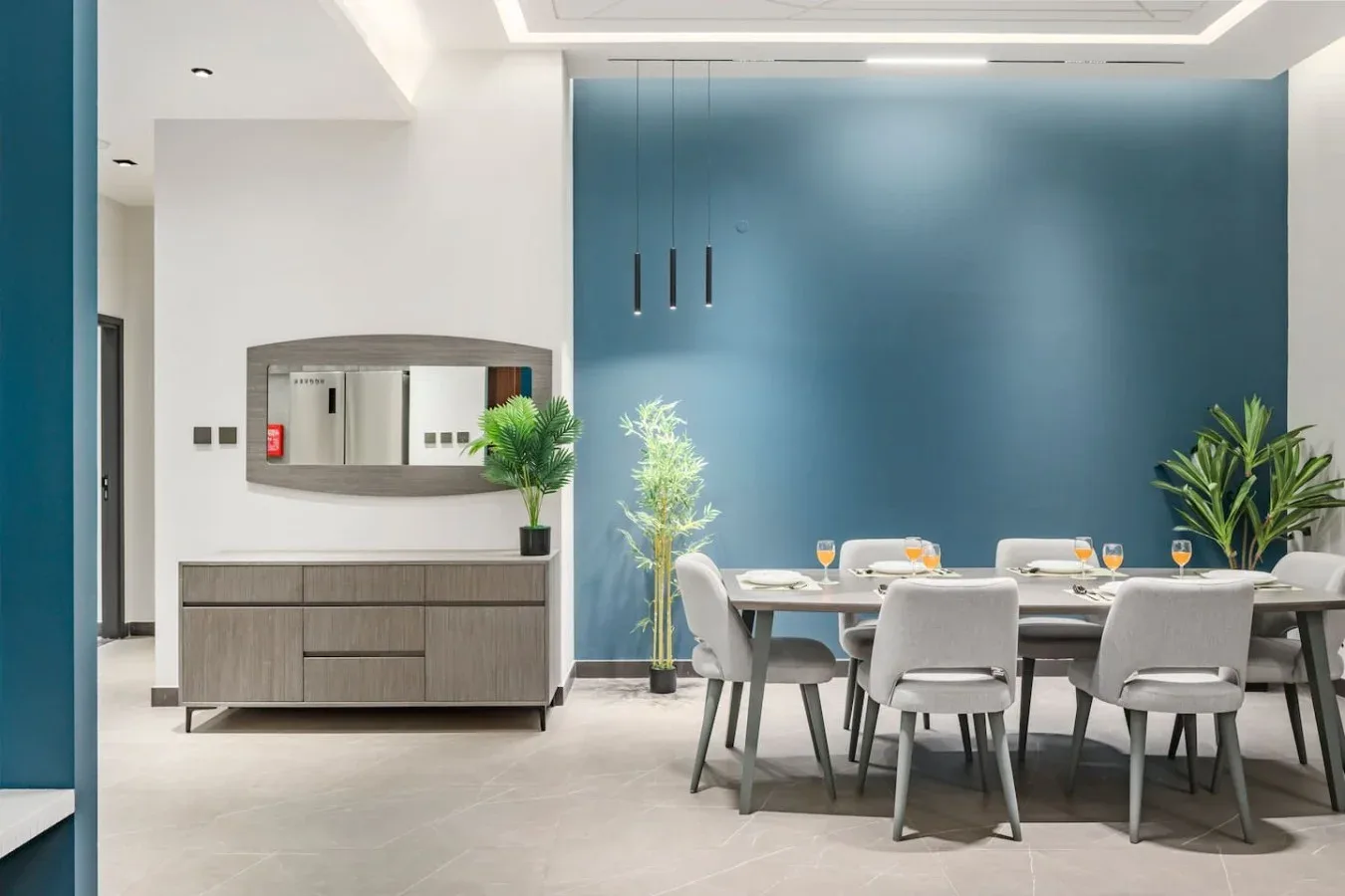 Un comedor moderno con una mesa y sillas junto a una pared azul.