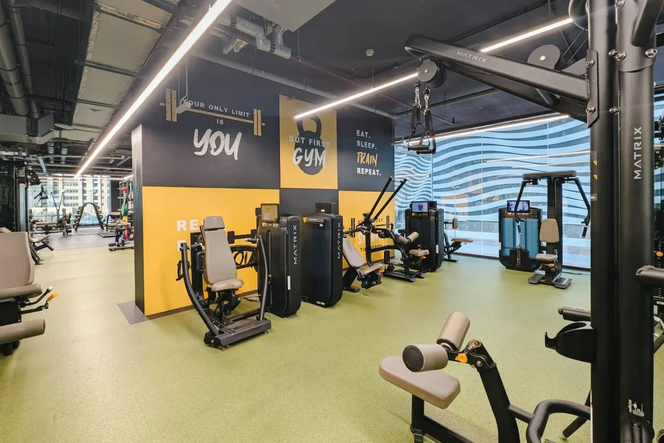 Un gimnasio con máquinas de ejercicio y equipo de entrenamiento distribuido por el espacio.