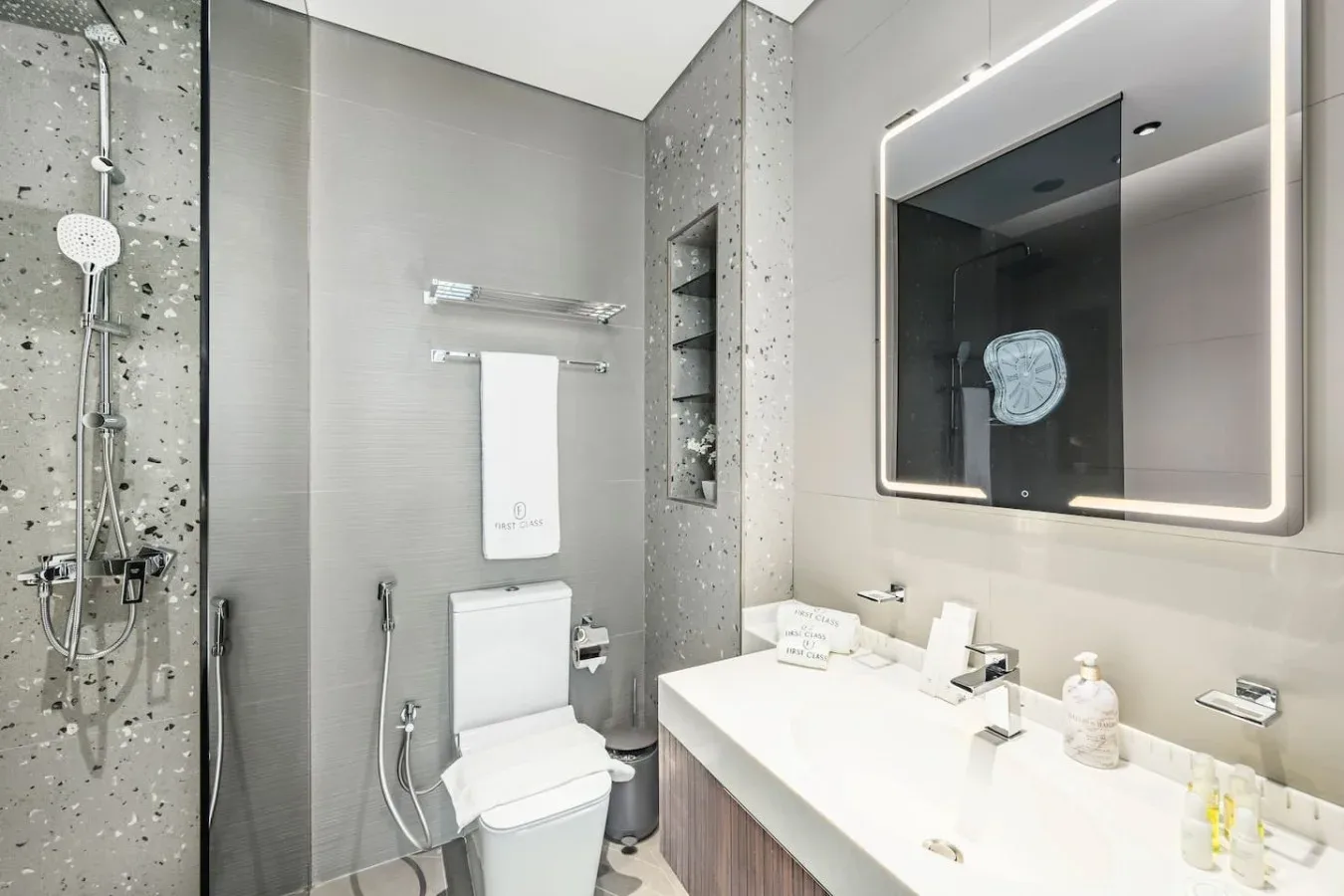 Un baño moderno con ducha, inodoro y un amplio lavabo.