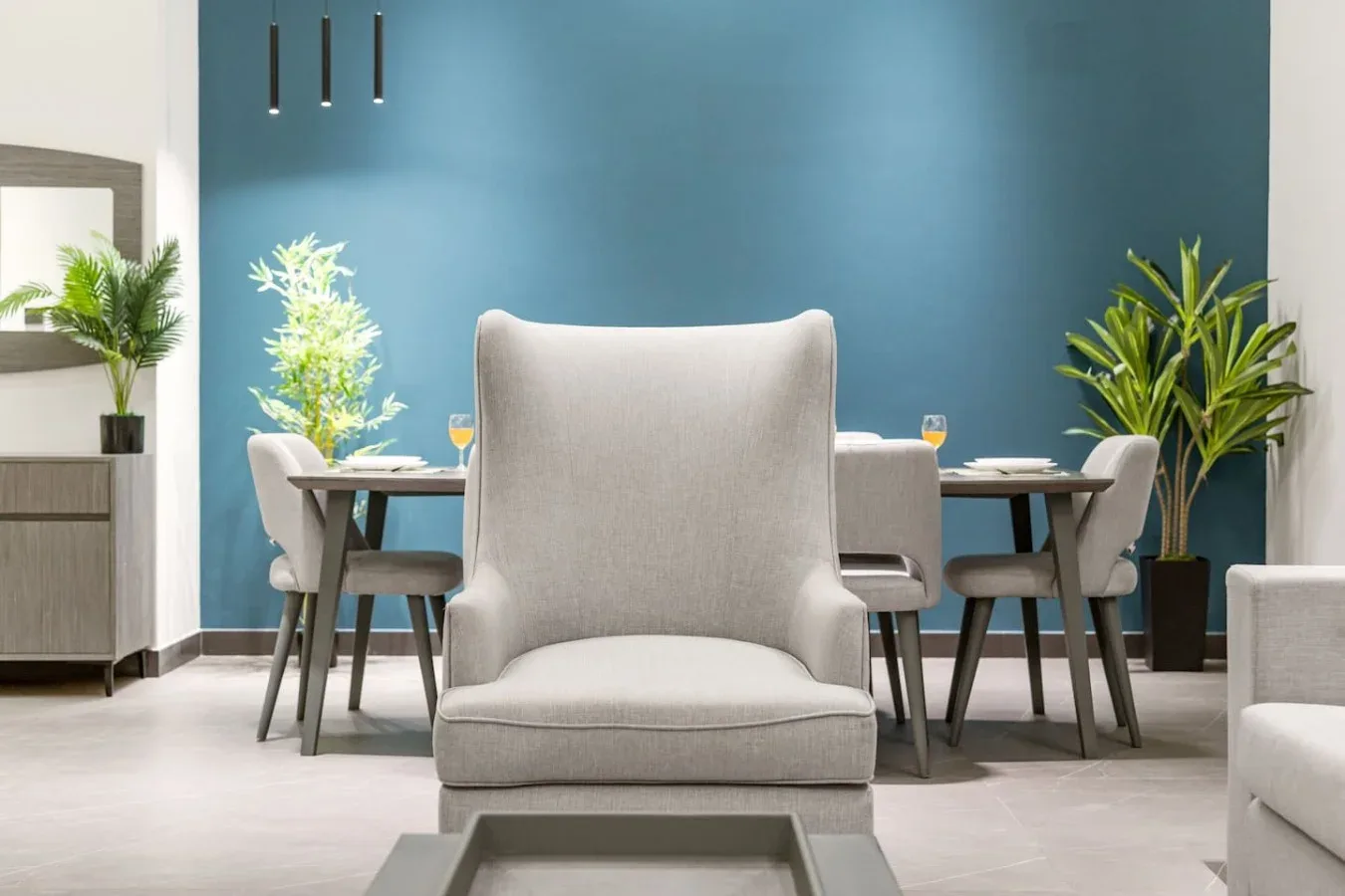 Un comedor con una mesa y sillas frente a una pared azul.
