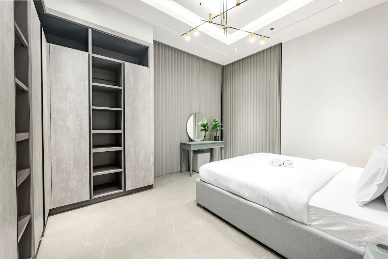 Un dormitorio luminoso con una cama, estanterías empotradas y una pequeña mesa de tocador.
