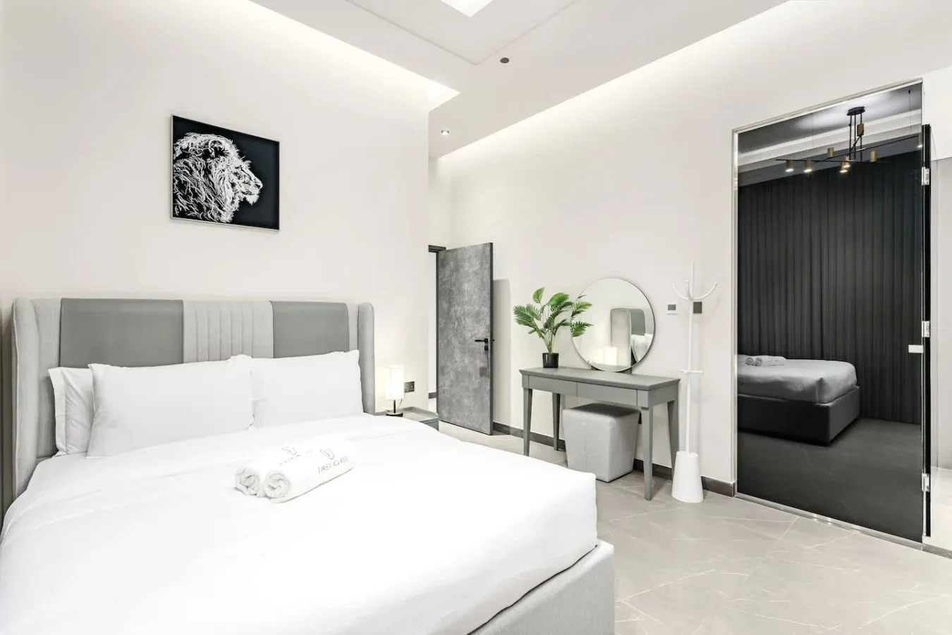 Un dormitorio luminoso con una cama grande y un tocador junto a la puerta.