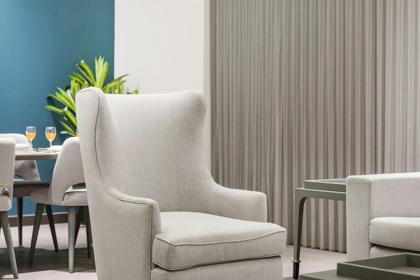 Una zona de estar con un sillón tapizado claro junto a una mesa pequeña.