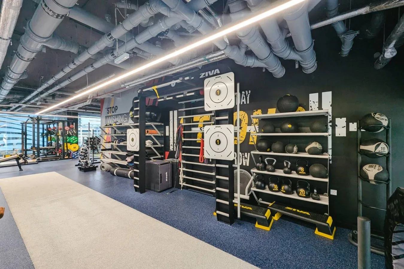 Zona de gimnasio con soportes para pesas, pesas rusas y equipo de ejercicio.