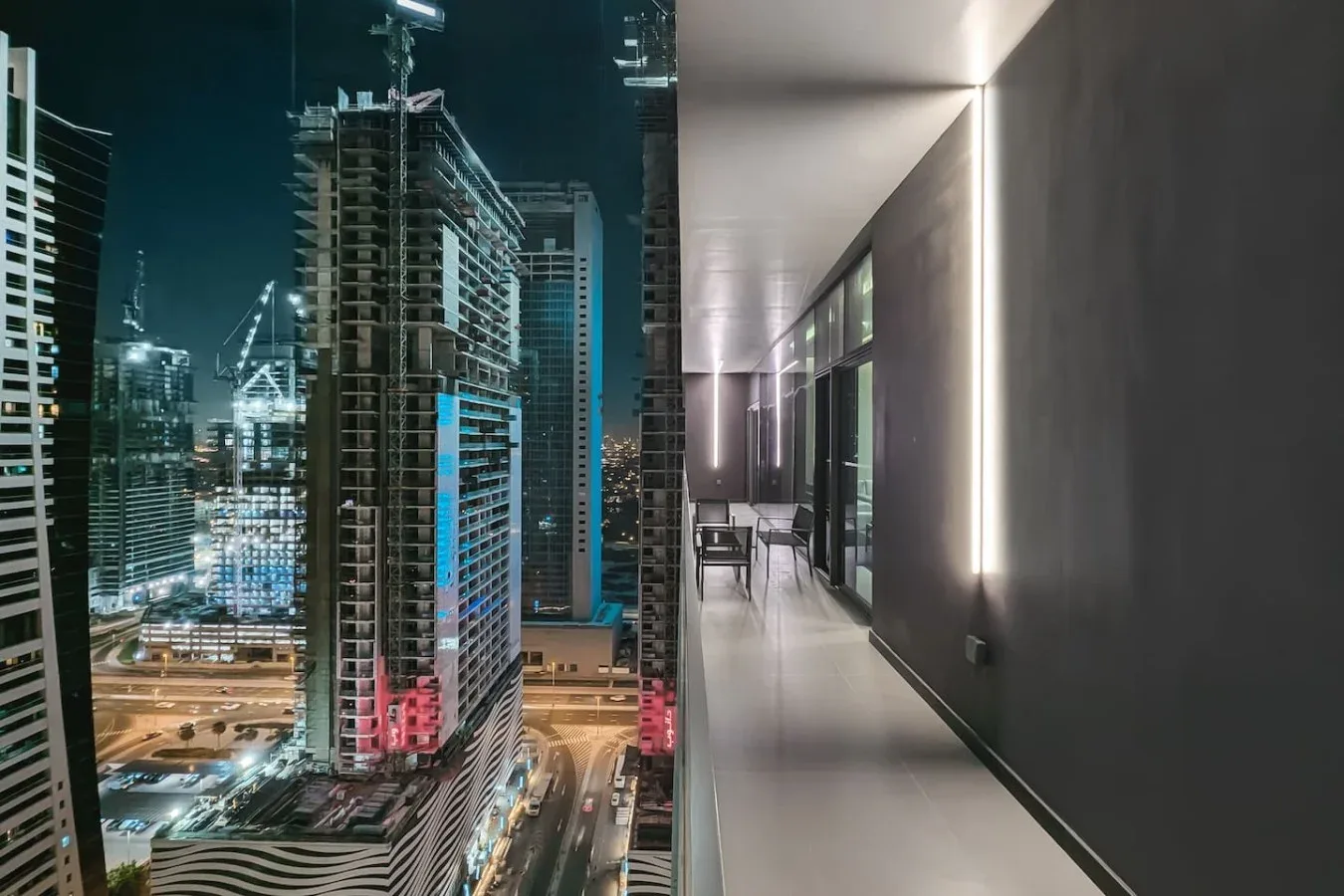 Un horizonte urbano nocturno se ve junto a un pasillo interior moderno.