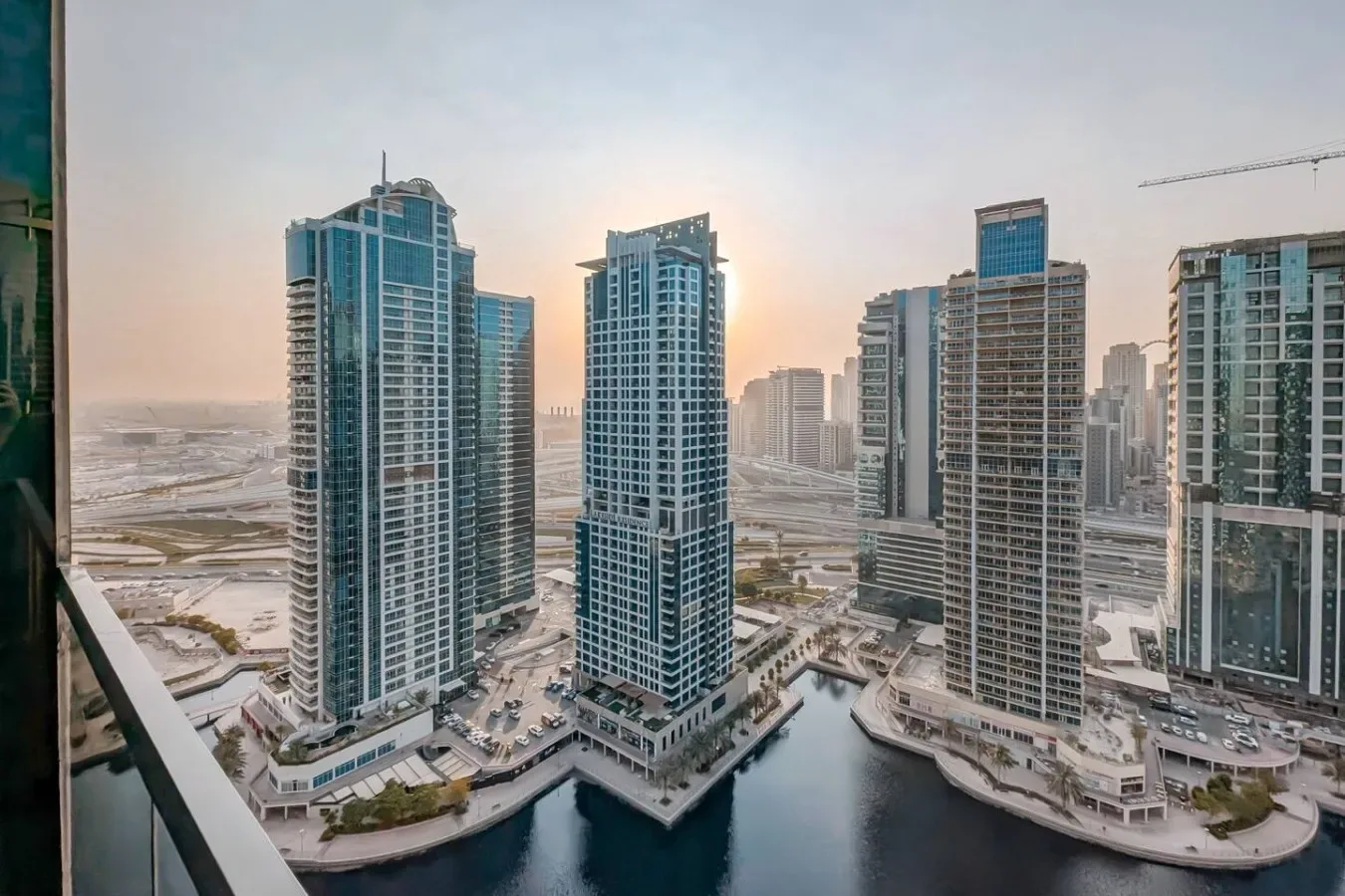 Edificios altos bordean un paisaje urbano junto al agua al atardecer.
