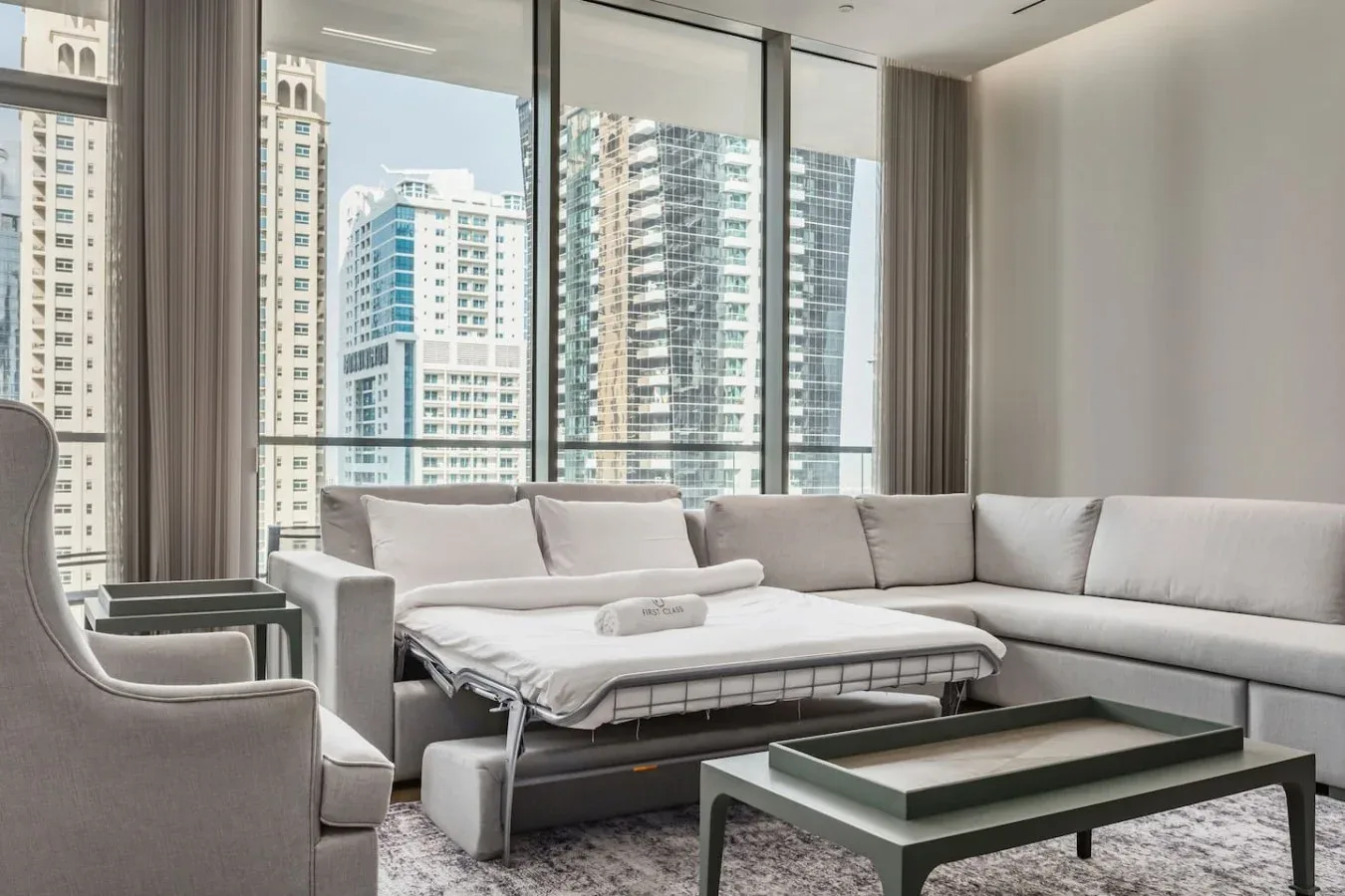 Una sala luminosa con asientos seccionales junto a grandes ventanas con vistas a edificios de la ciudad.