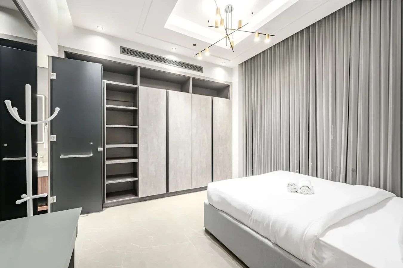 Un dormitorio con una cama bien hecha, armarios empotrados y cortinas largas.
