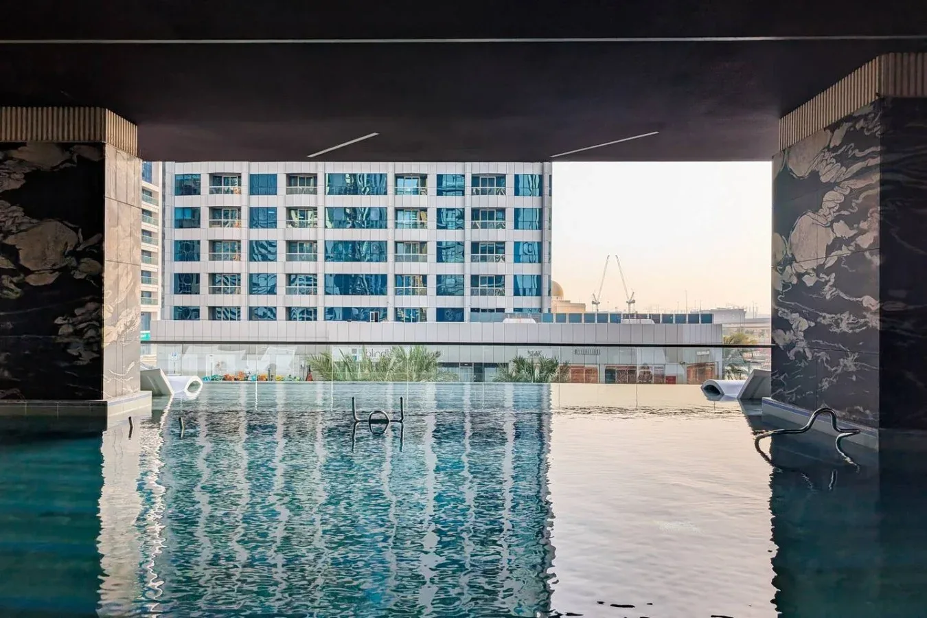 Una piscina en la azotea da a un edificio moderno, enmarcada por paredes con motivos decorativos.