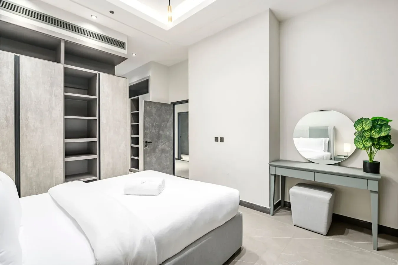 Un dormitorio luminoso con una cama bien arreglada y un tocador.