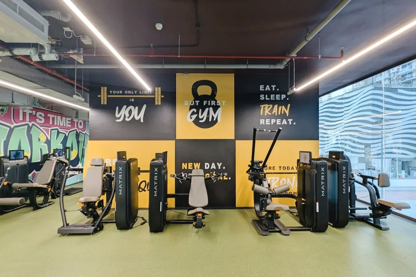 Un gimnasio con máquinas de ejercicio y gráficos motivacionales coloridos en las paredes.