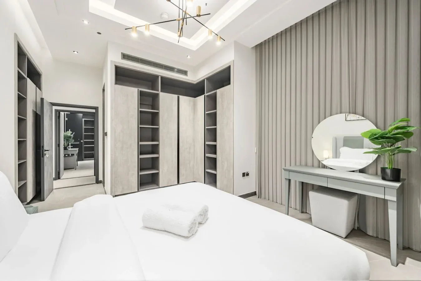Un dormitorio luminoso con estanterías empotradas y un tocador junto a la cama.