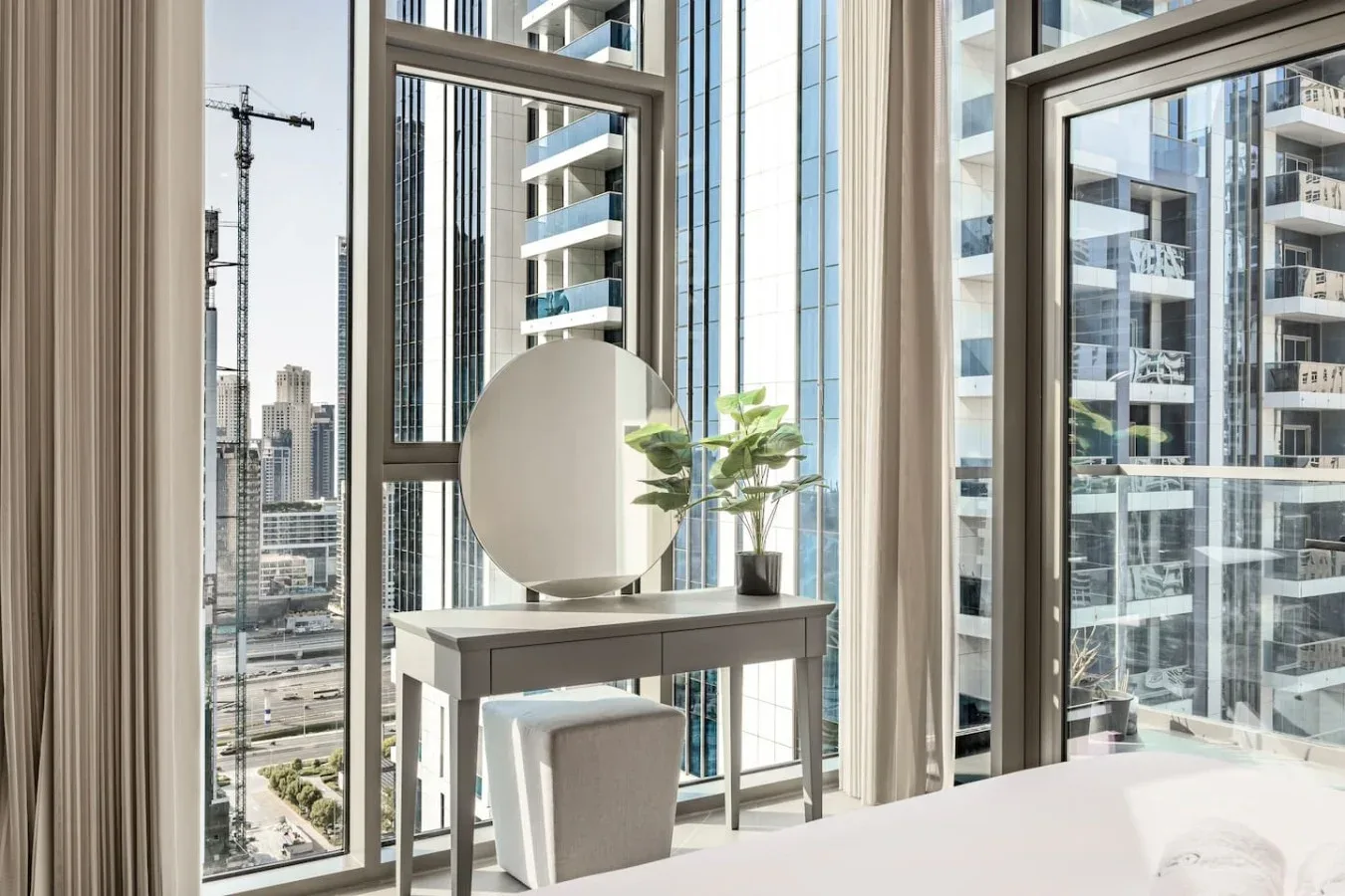 Una habitación luminosa con ventanales de piso a techo y edificios altos a la vista.