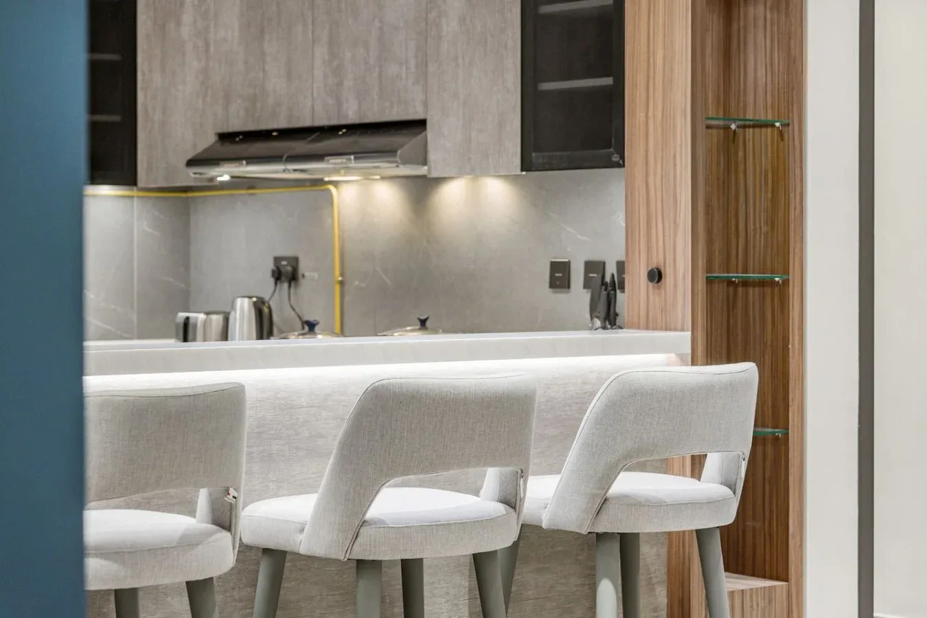 Una cocina moderna con una barra, iluminación colgante y asientos tapizados.