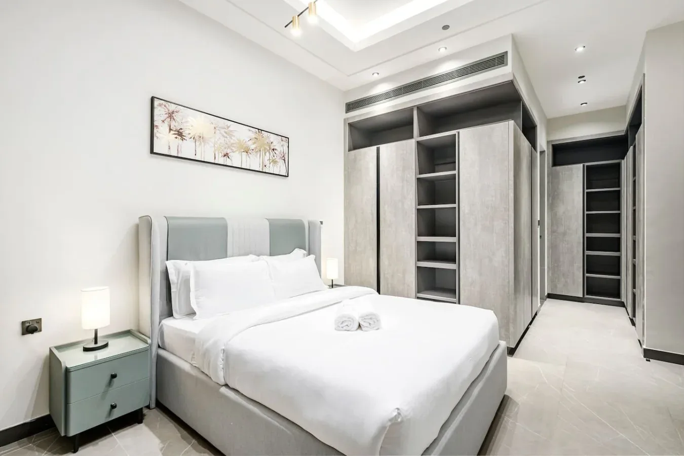 Un dormitorio con una cama tendida junto a estanterías empotradas.