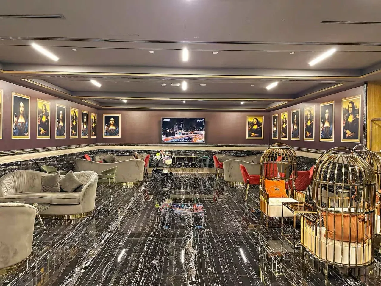 Un salón con asientos, cuadros enmarcados y un televisor al fondo.