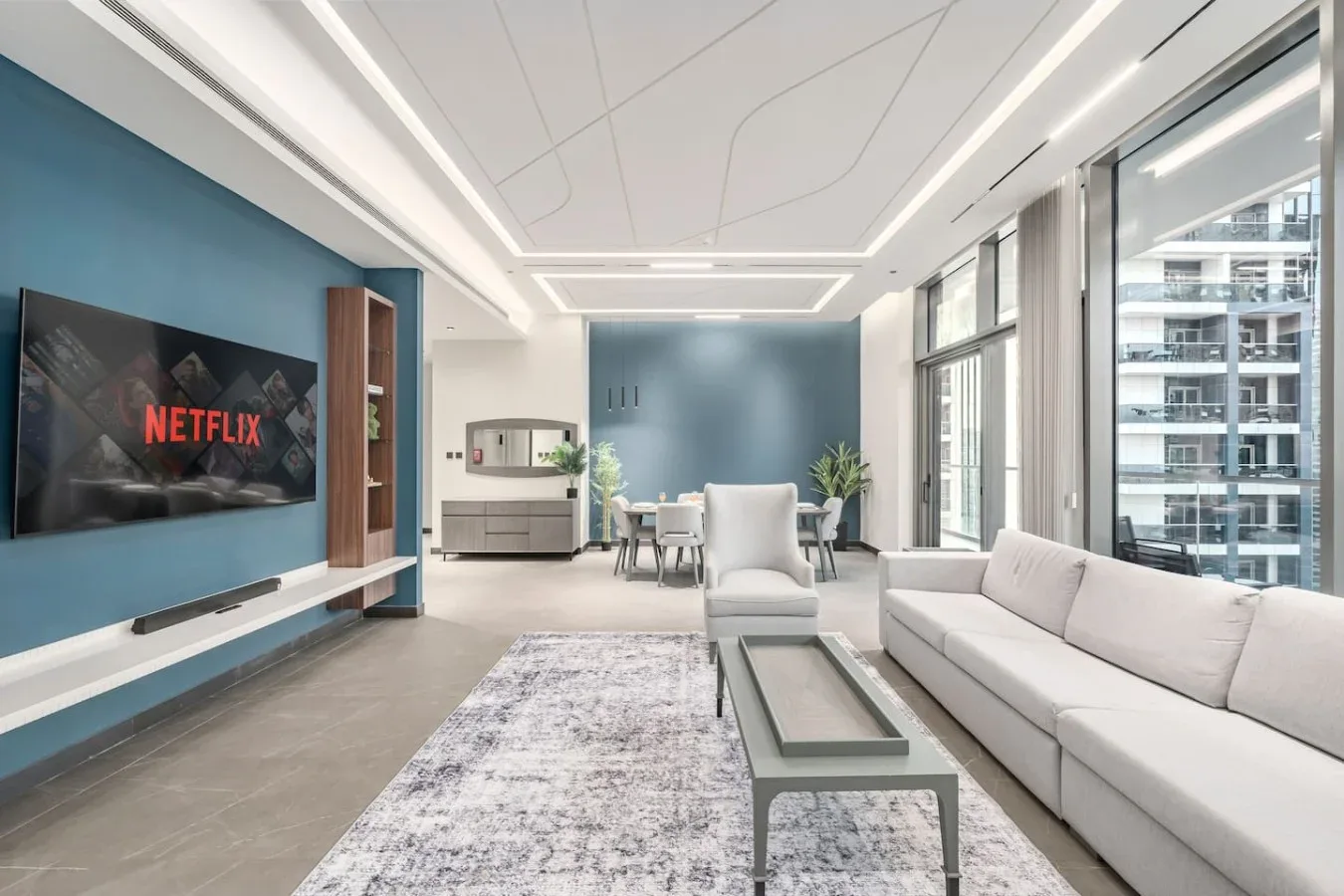 Una sala de estar moderna y luminosa con asientos, una mesa de centro y grandes ventanas.