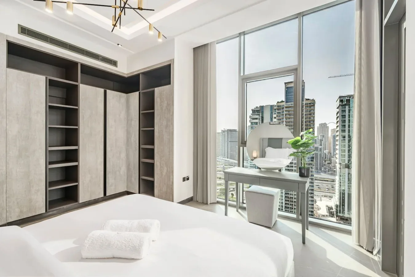 Un dormitorio luminoso con estanterías empotradas y un escritorio junto a grandes ventanales.