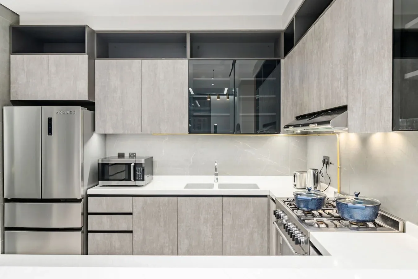 Una cocina moderna con gabinetes grises, un refrigerador y una estufa.
