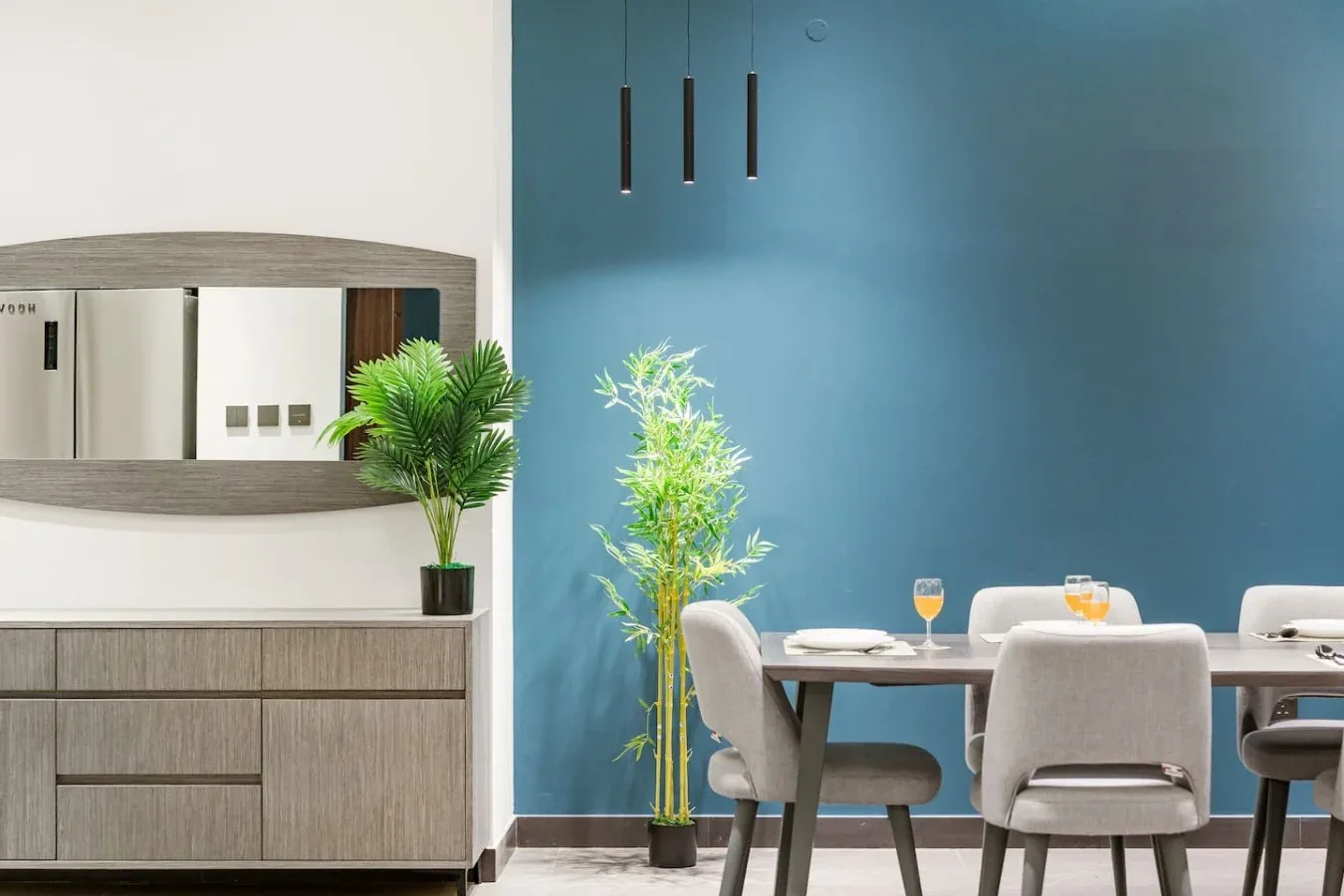 Comedor con mesa y sillas junto a una pared azul.