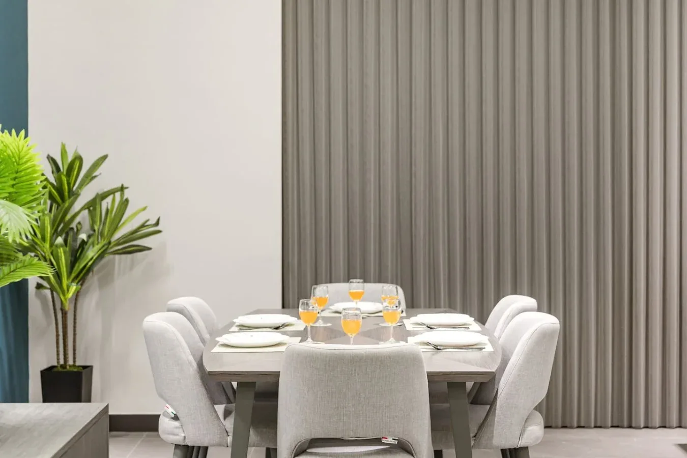 Comedor con una mesa puesta con platos y asientos tapizados.