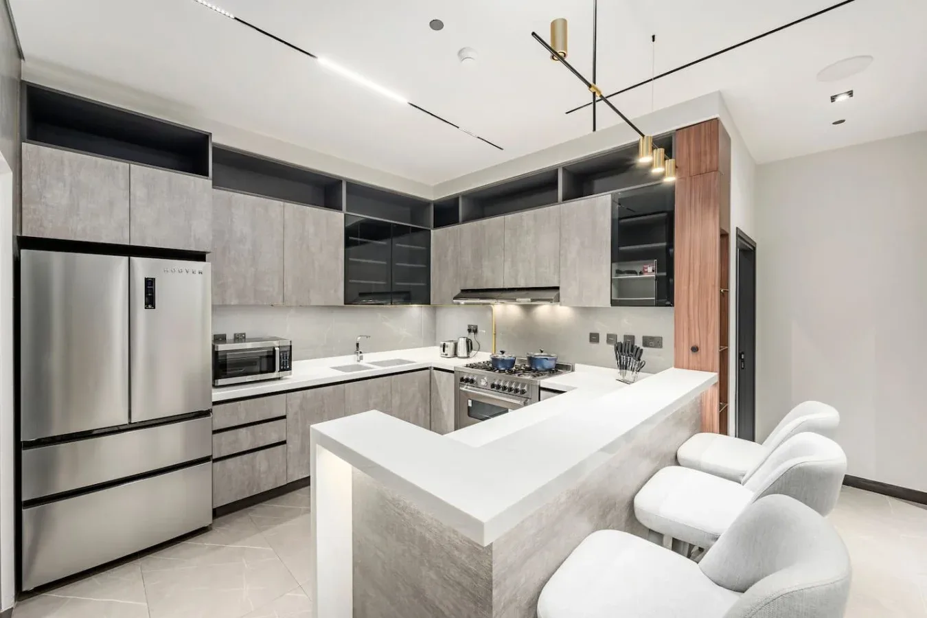 Una cocina moderna con gabinetes grises y una isla blanca con asientos.