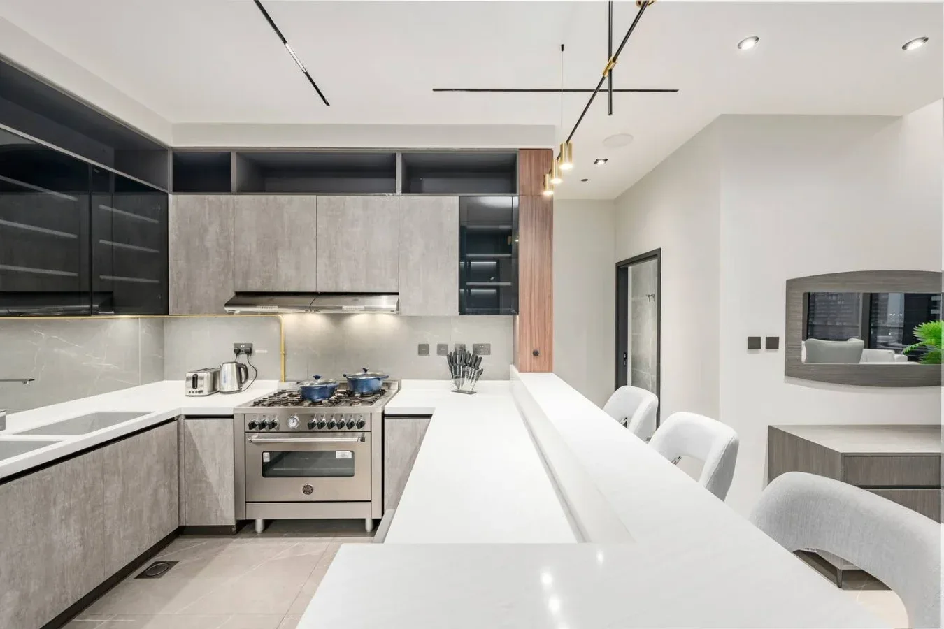 Una cocina moderna con gabinetes oscuros, una estufa y una larga encimera blanca.