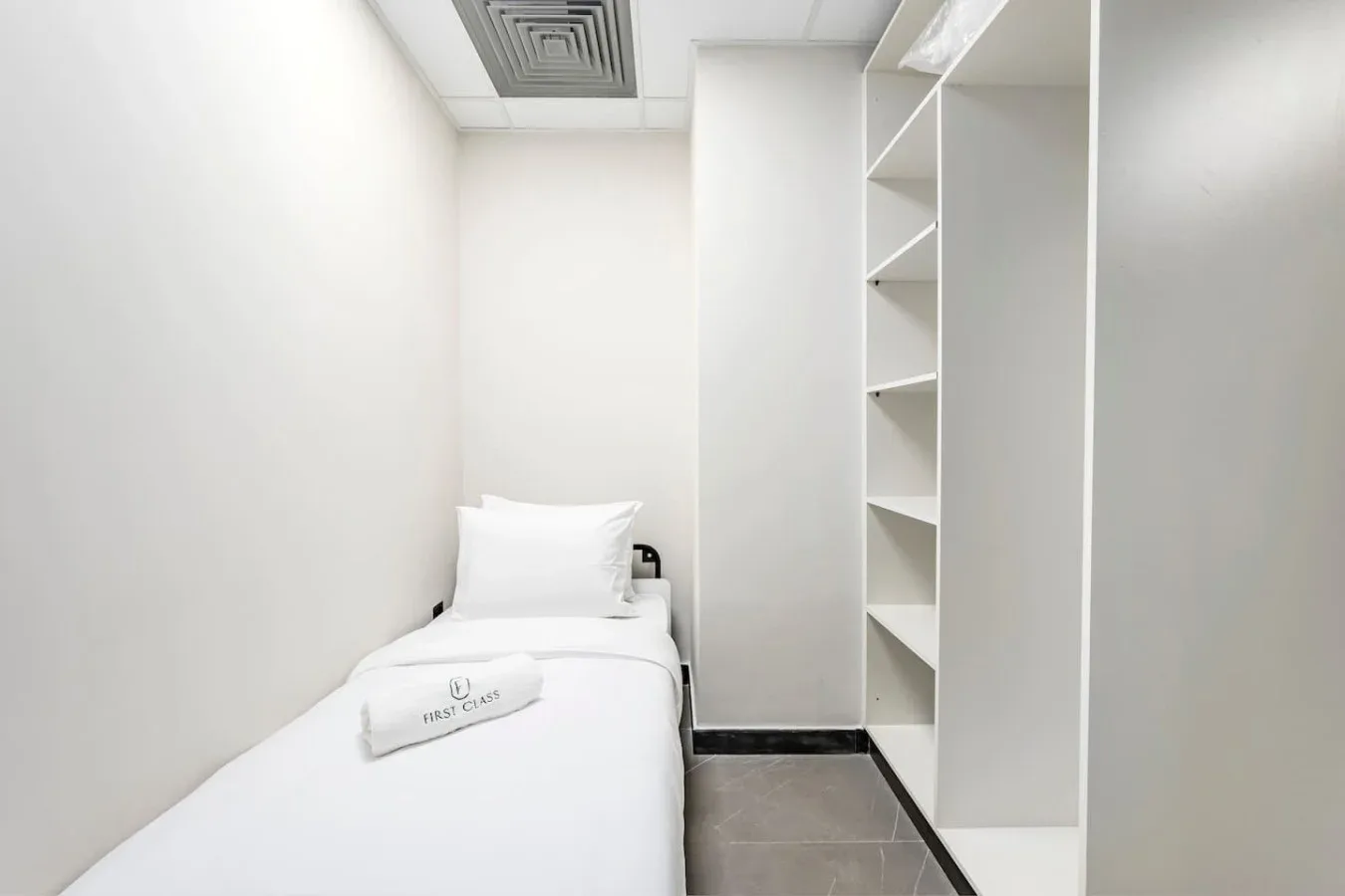 Un dormitorio compacto con una cama individual y estanterías abiertas.