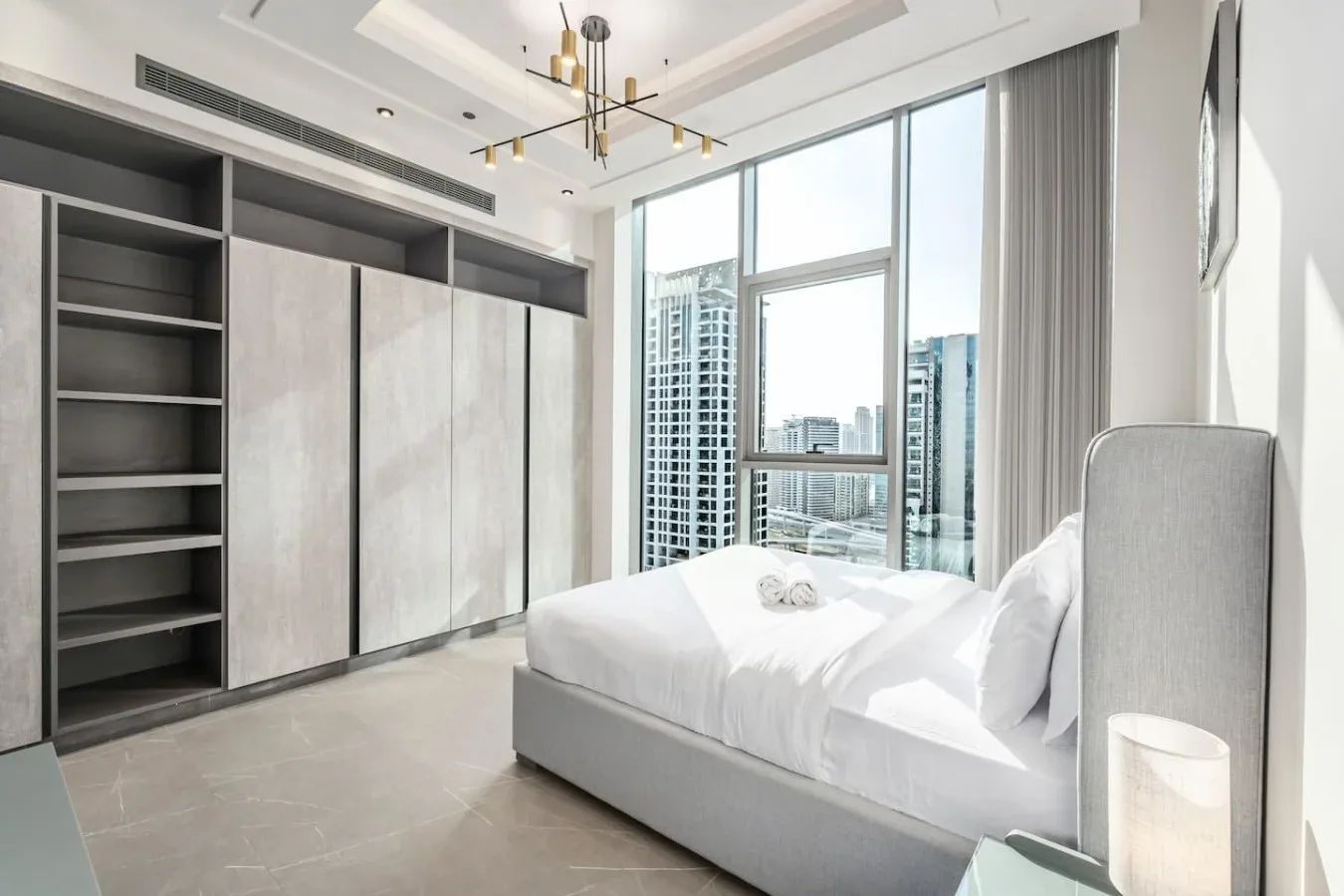 Un dormitorio luminoso con una cama grande junto a ventanales.
