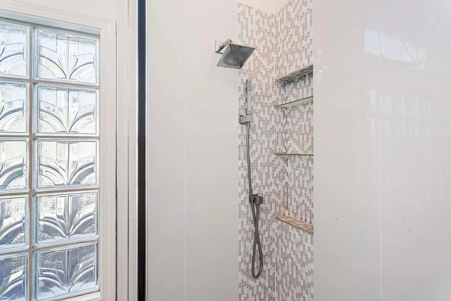 A tiled shower beside a decorative glass-block window.