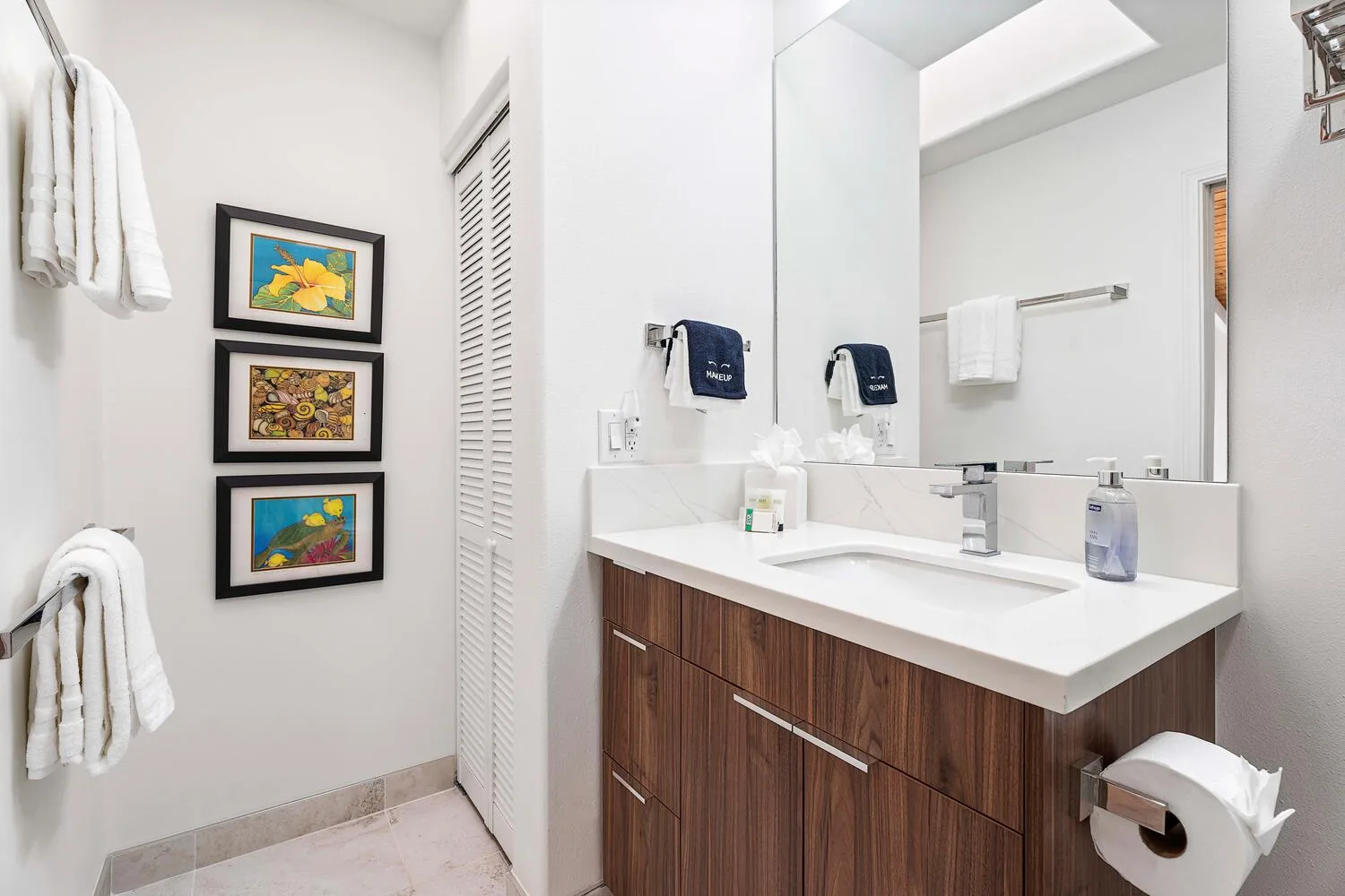 A bathroom vanity with a wide mirror and folded towels on the wall.