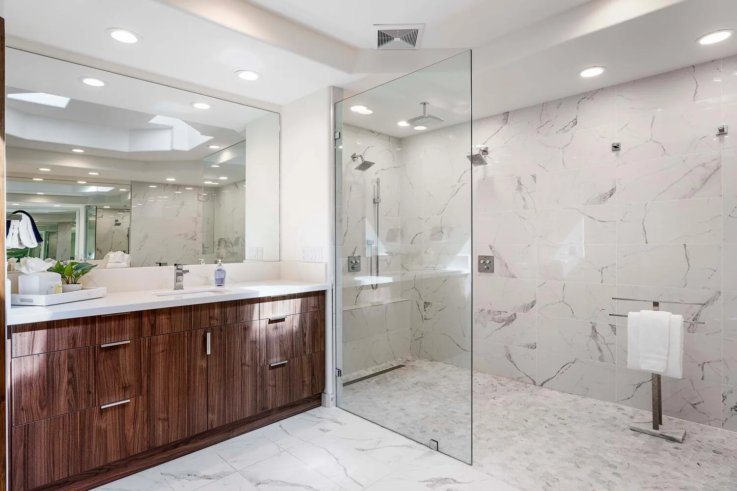 A bright bathroom with a long vanity and a glass shower.