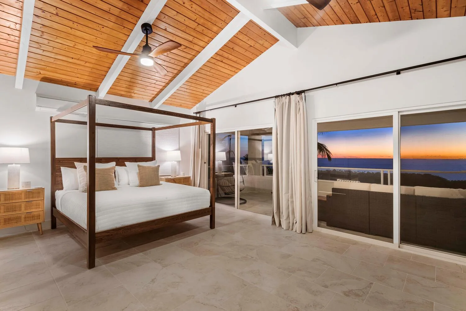 A bedroom with a canopy bed and sliding glass doors opening onto a balcony.