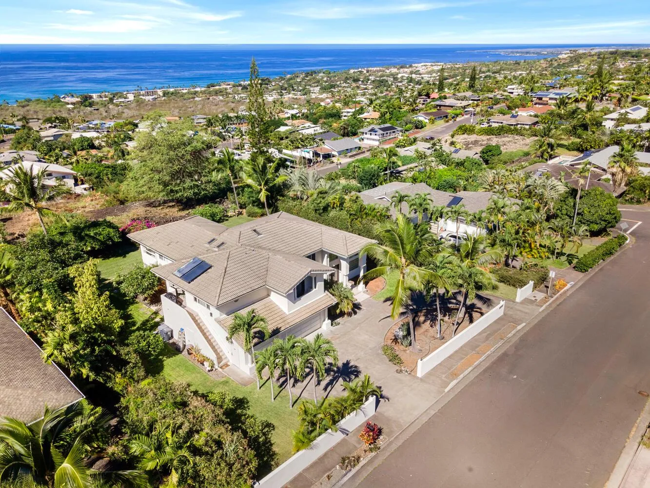 Aerial view of a coastal neighborhood with homes, greenery, and the ocean.