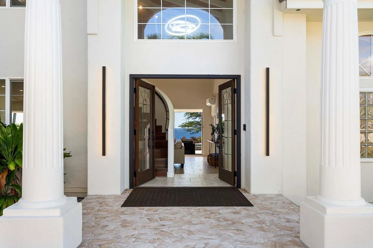 A bright entryway with open double doors and tall white columns.