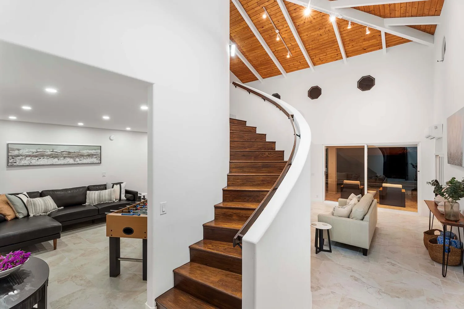 A bright living area with a curved wooden staircase and seating.