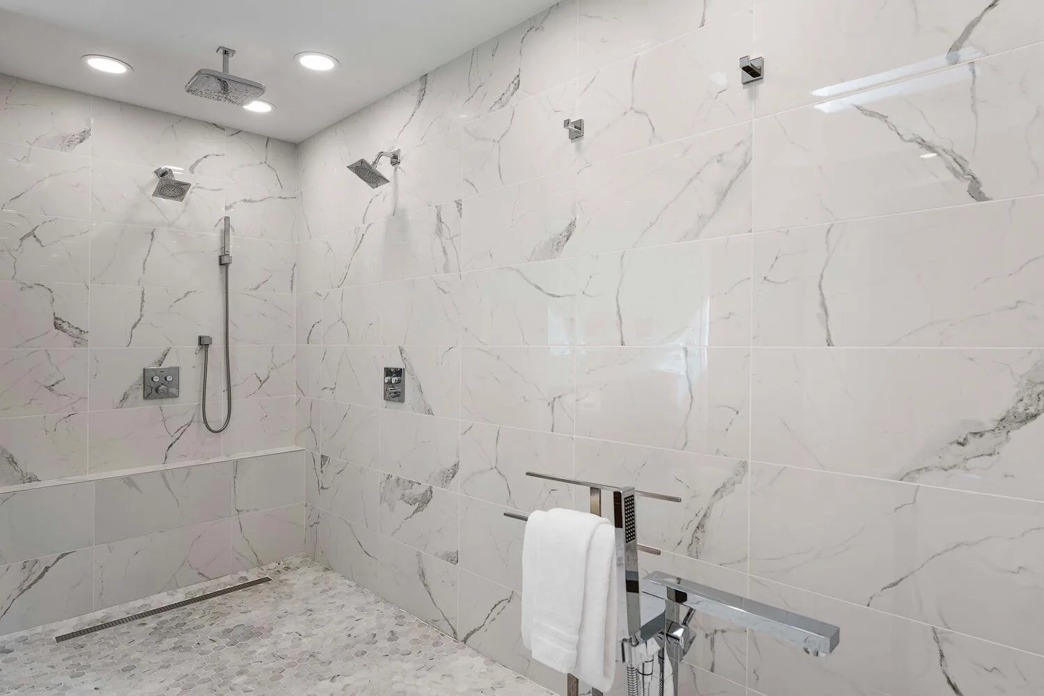 A tiled shower area with a handheld showerhead and towel.
