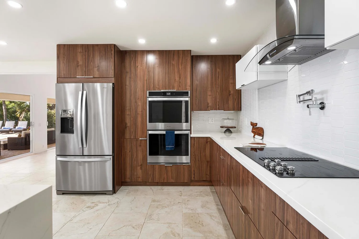 A modern kitchen with wood cabinetry, stainless steel appliances, and white countertops.