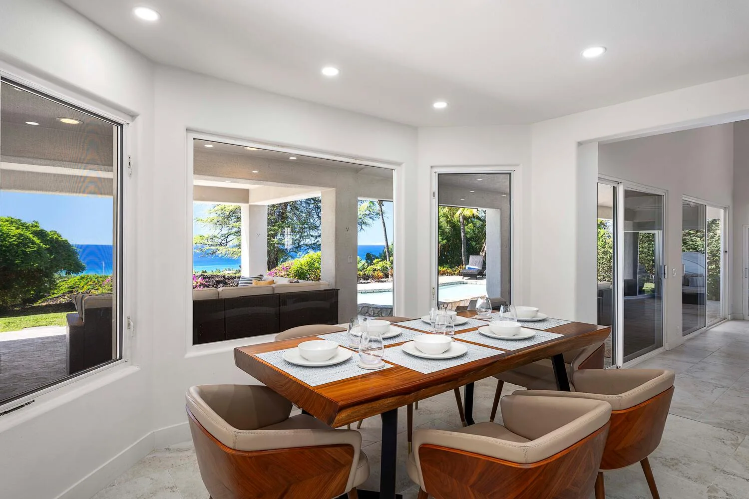 A dining area with a set table and views of the garden and sea.