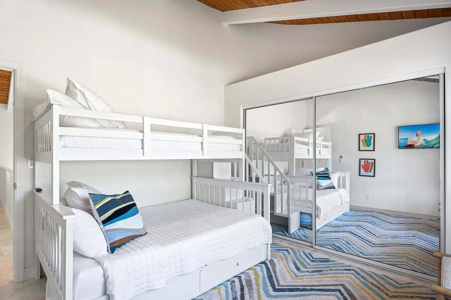 A bedroom with white bunk beds and a patterned rug.