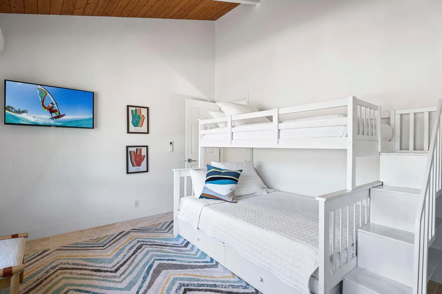 A bedroom with white bunk beds and a geometric rug.